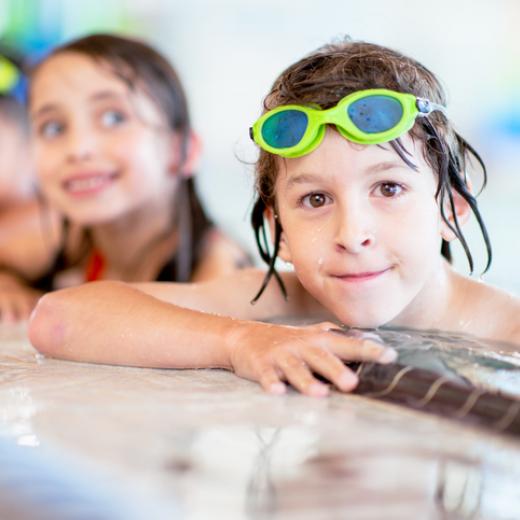 Smiling children along the side of a pool