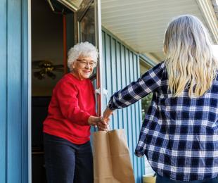 Volunteer handing a bag of food to a senior citizen