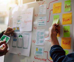 People putting website design elements on a large white board